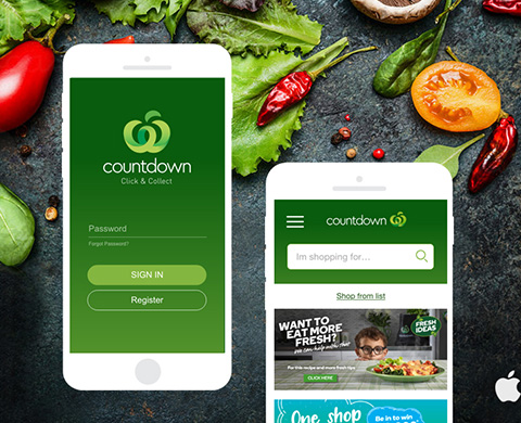 Two smartphones displaying the Countdown grocery app interfaces on a dark surface with fresh vegetables around them.